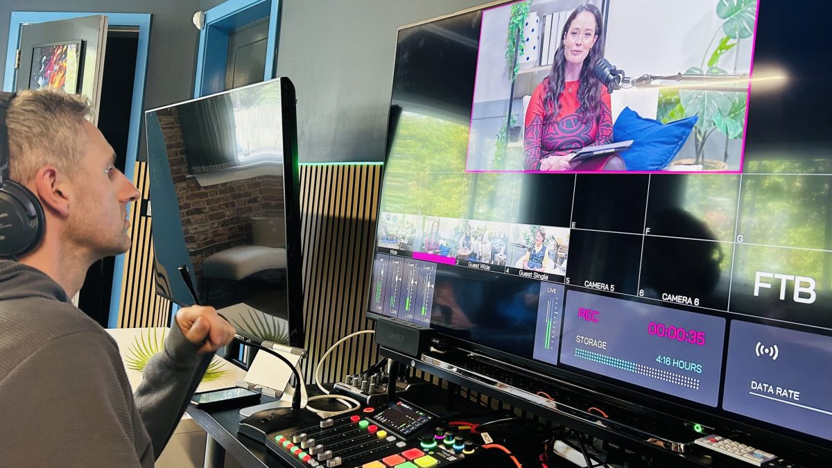 A photo of a man at a control desk, editing the SWI History Members Podcast, on the Screen is podcast host Jennifer Reoch
